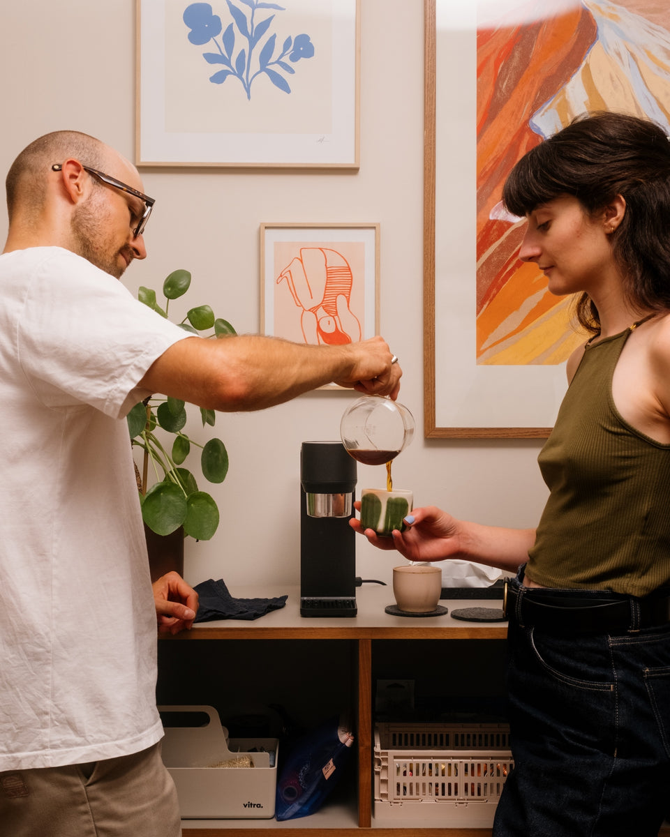 Coffee poured from a carafe into a cup, with bre:zi on the counter