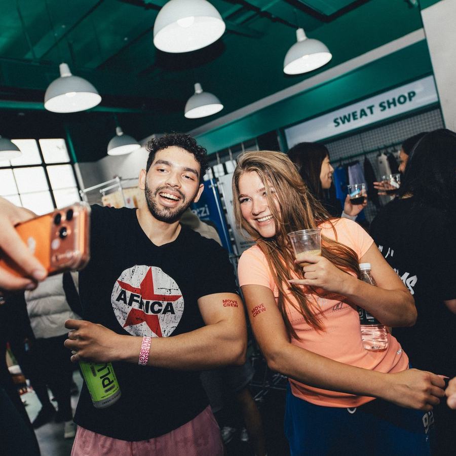 Three people crowded into a phone camera, laughing, holding cups of cold brew